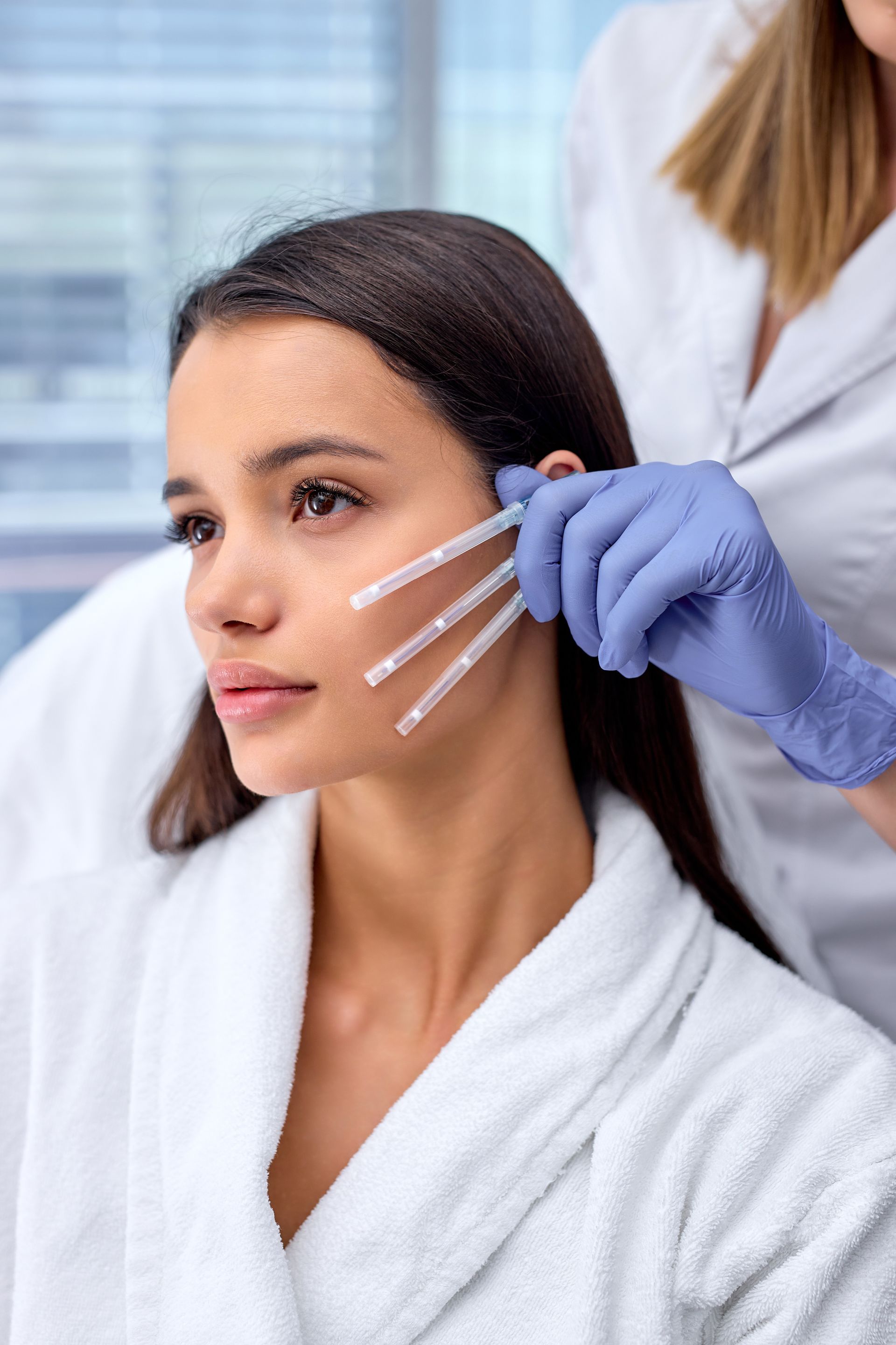 a woman in a white robe is getting a thread lift facial treatment