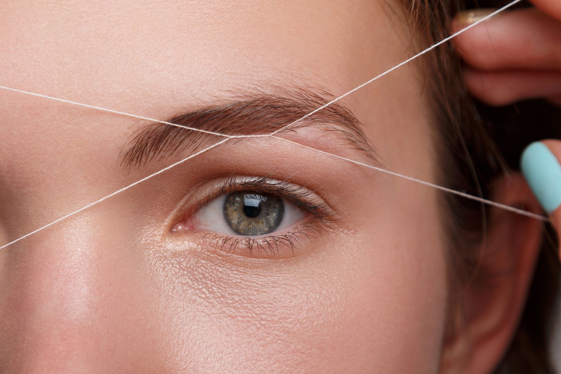 a woman has her eyebrows threaded with a string