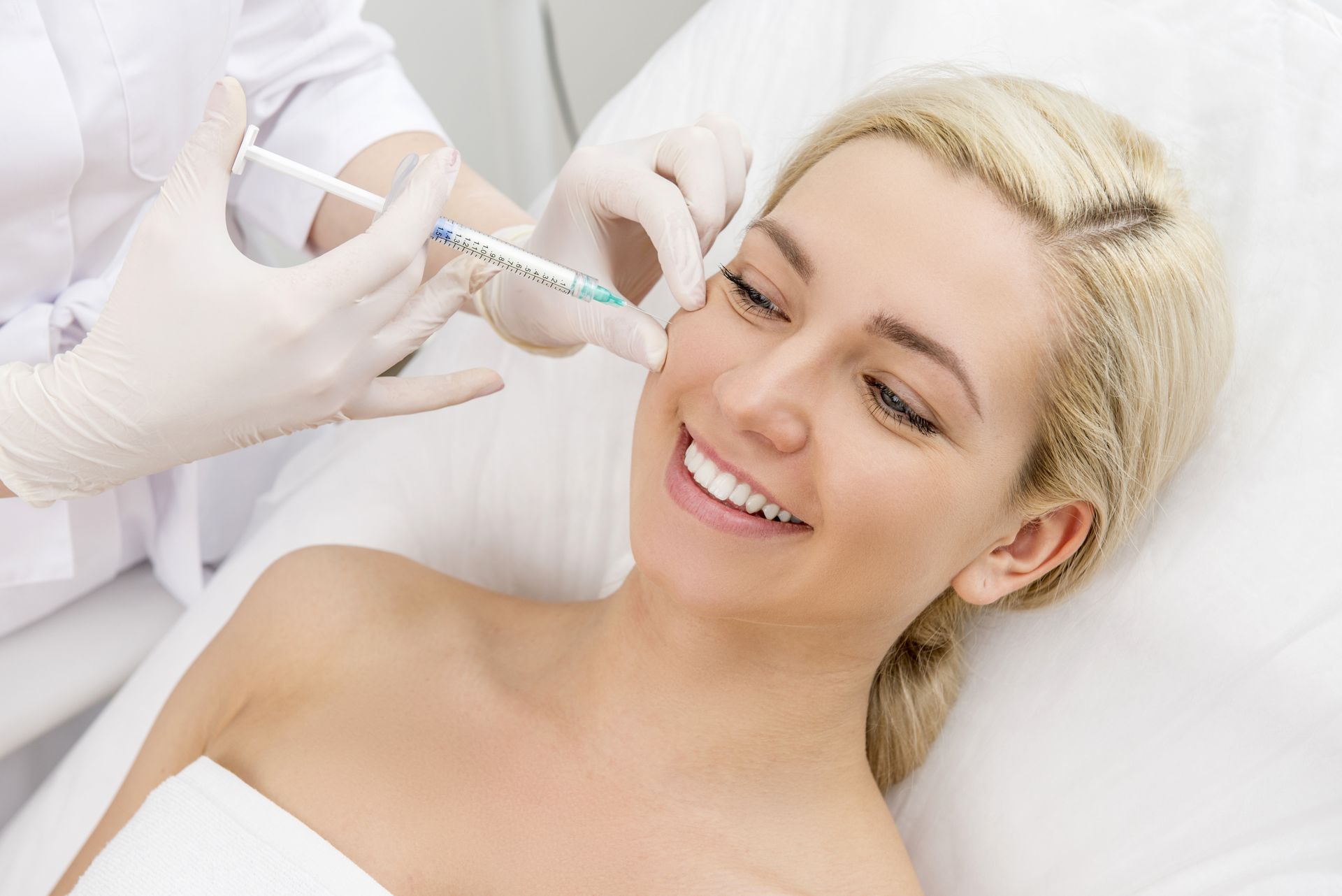 a woman is smiling while getting a botox injection in her face