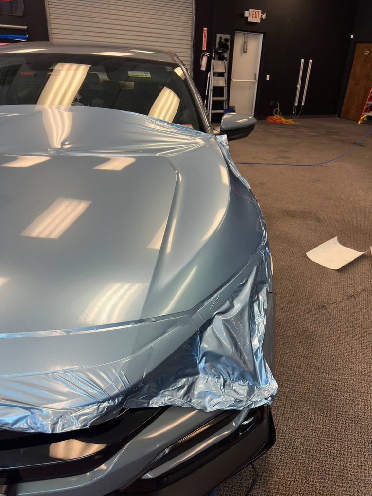 A car is wrapped in aluminum foil in a garage.