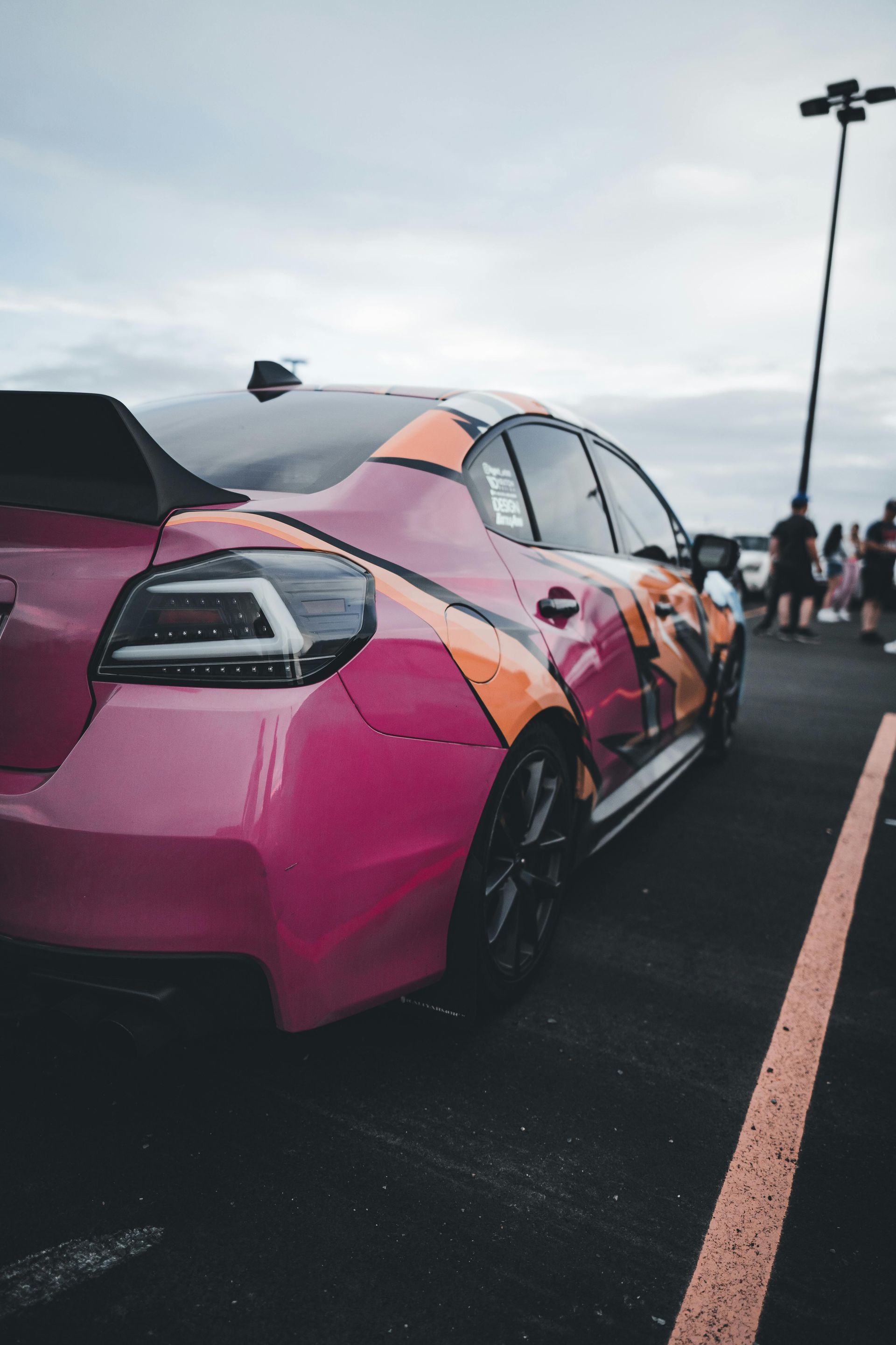 A pink and orange car is parked in a parking lot.