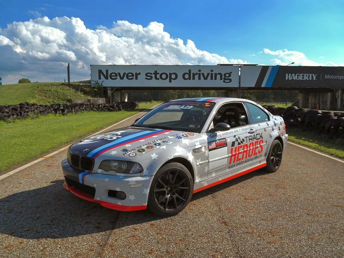 A race car is parked in front of a sign that says never stop driving.