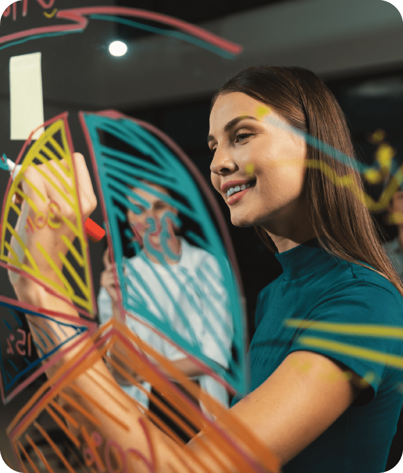 A woman is drawing on a glass wall with a marker.