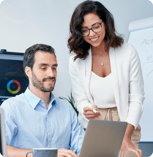 A man and a woman are looking at a laptop computer.