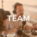 A man wearing headphones speaks into a microphone, recording. The word 