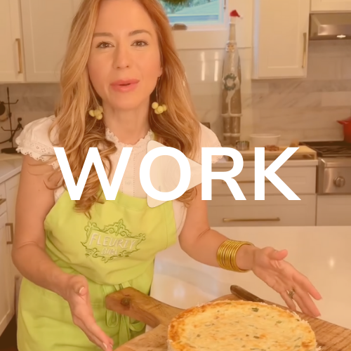 Woman in kitchen wearing green apron, pointing at food.