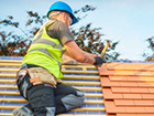 a man is working on a roof with a hammer .