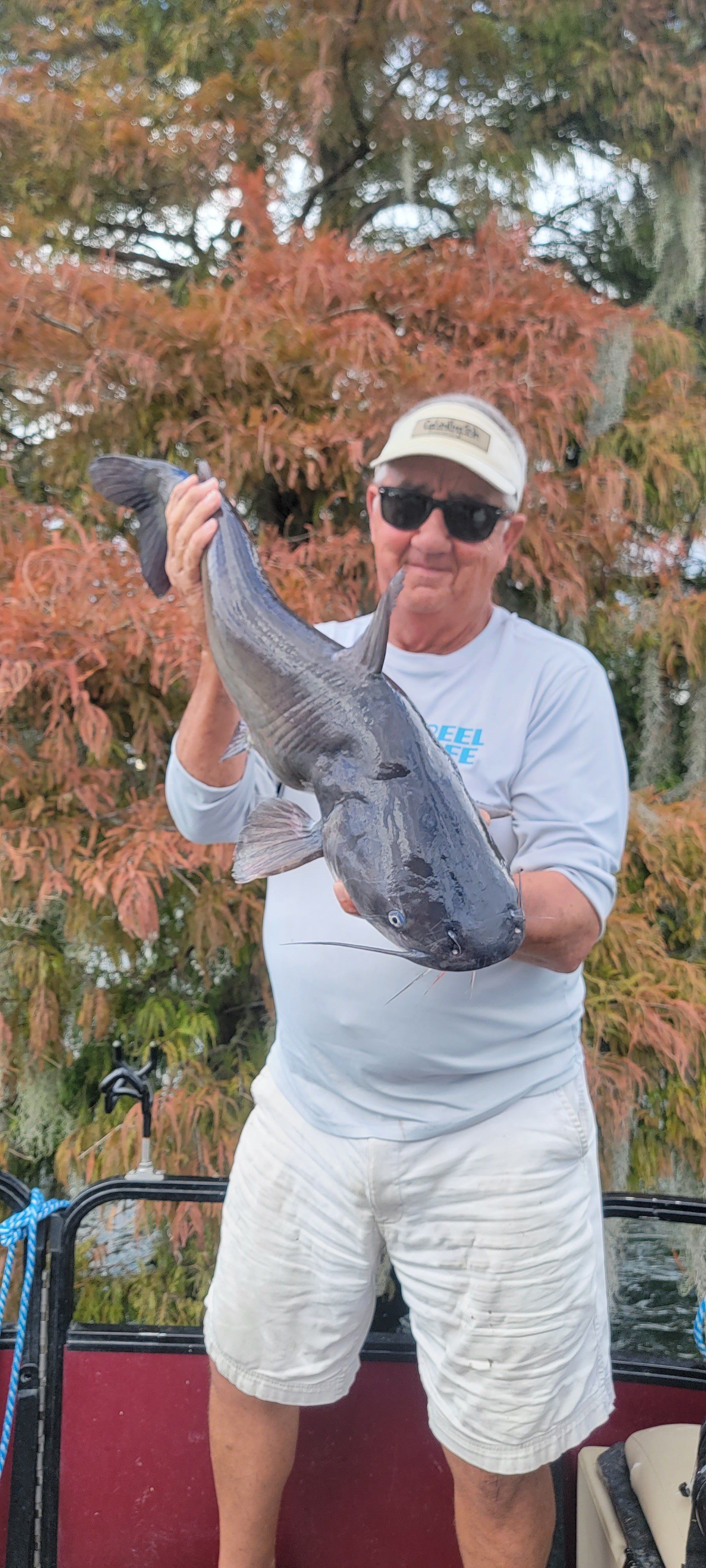 Man with sunglasses holding a giant catfish