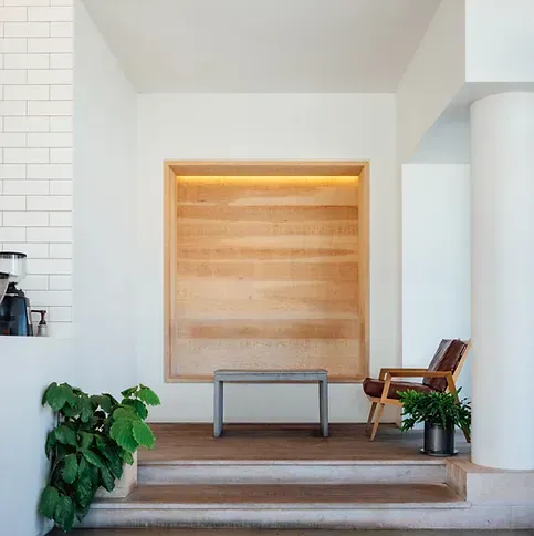 A room with a bench and chair in front of a wooden wall