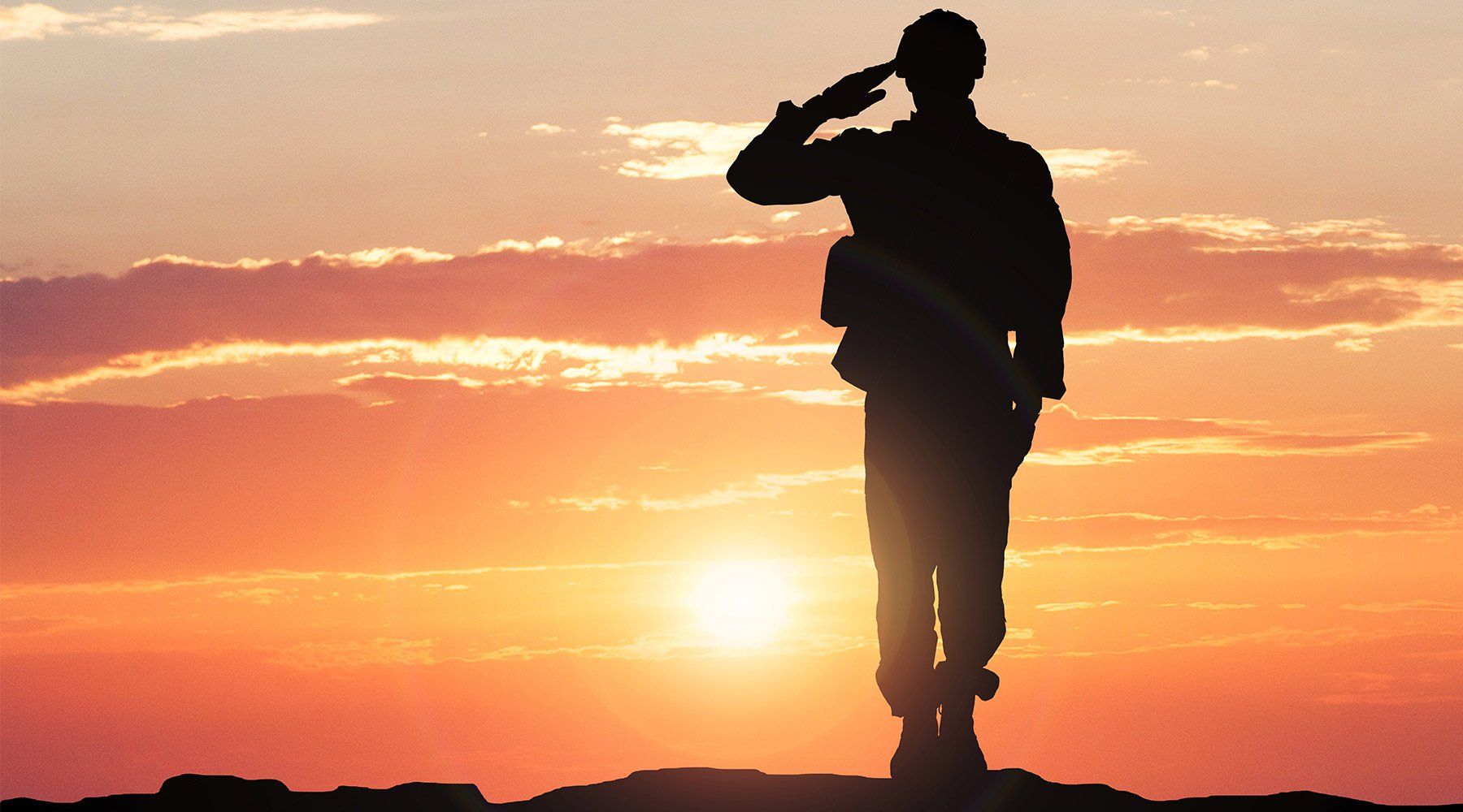 A silhouette of a soldier saluting during sunset