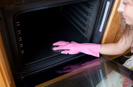 woman wiping the oven