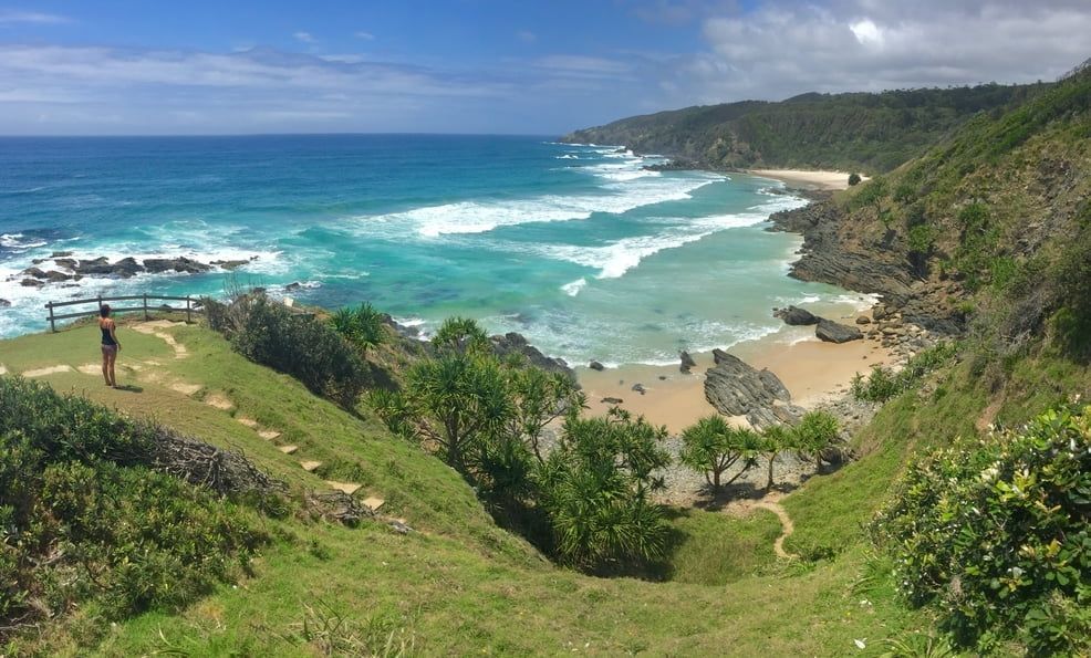 A Person is Standing on a Cliff Overlooking a Beach — HJK Plastering In Byron Bay, NSW