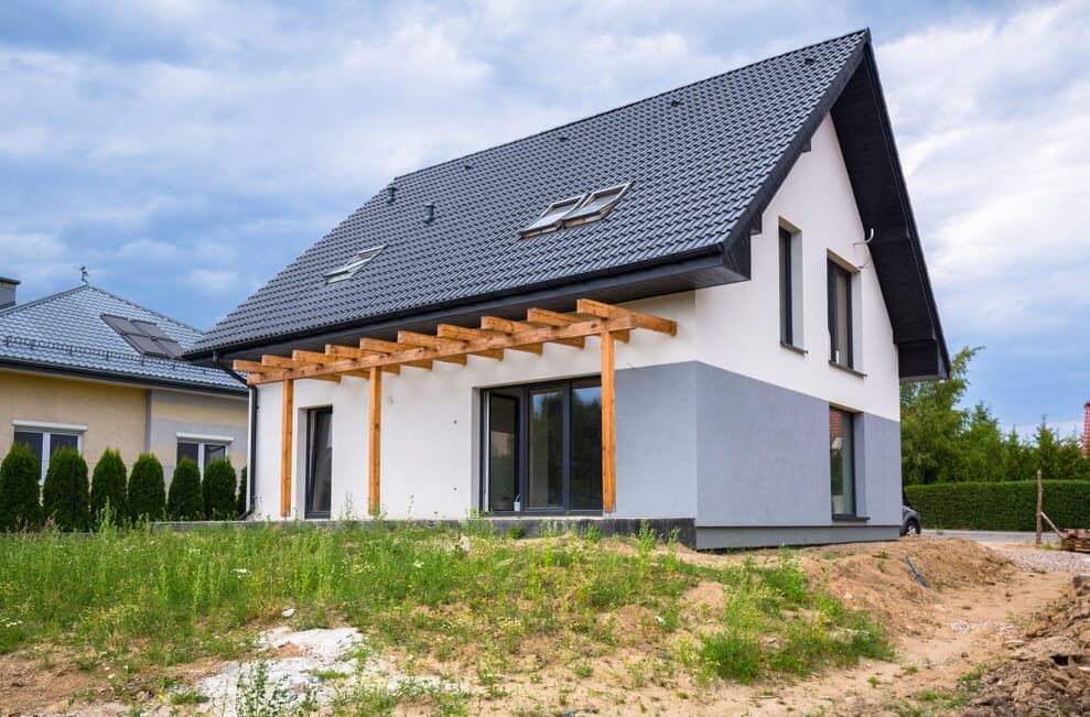 A White House With a Black Roof is Sitting on Top of a Dirt Hill — HJK Plastering In Byron Bay, NSW