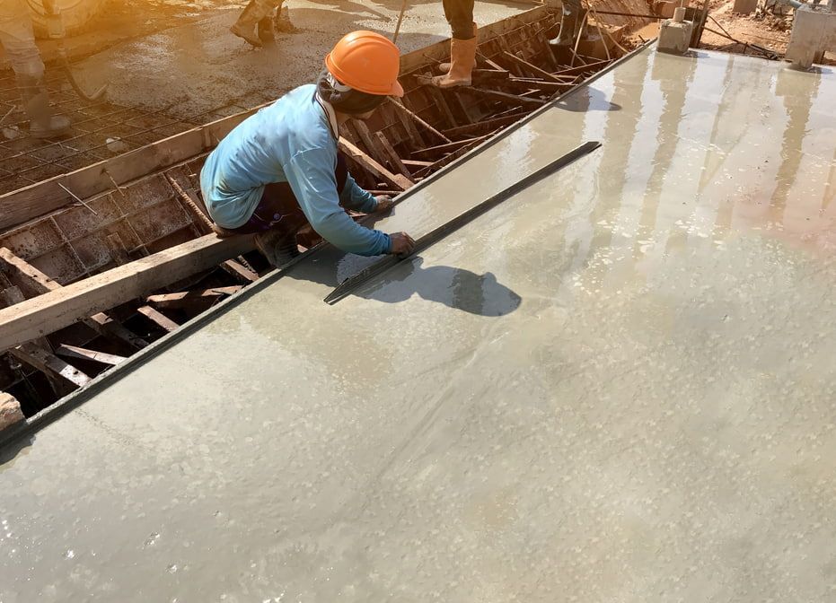 A Construction Worker is Measuring a Concrete Floor With a Ruler — HJK Plastering In Lennox Head, NSW