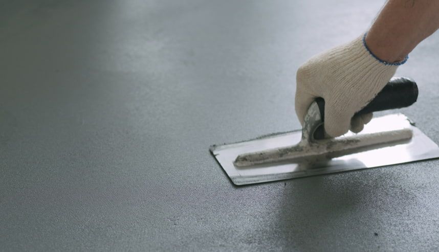 A Person is Using a Trowel on a Concrete Floor — HJK Plastering In Kyogle, NSW