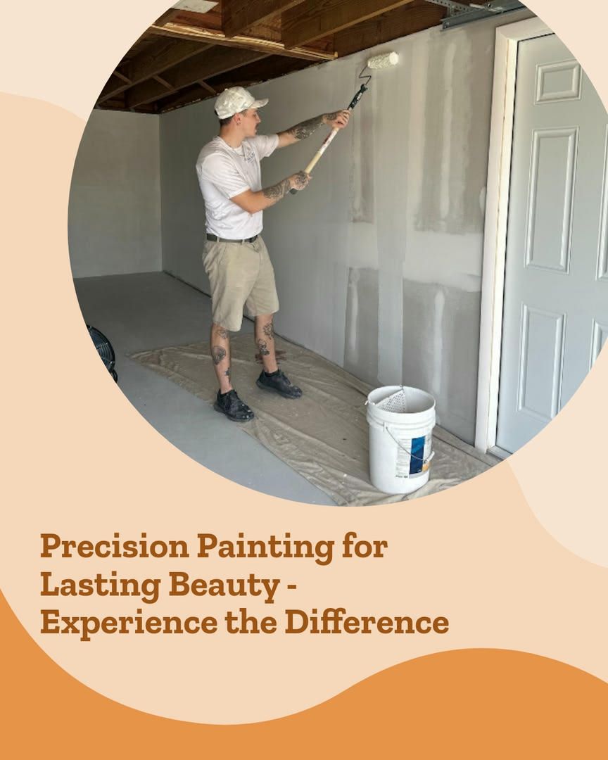 Painter using roller, applying paint to a wall in a garage. Bucket and drop cloth visible.