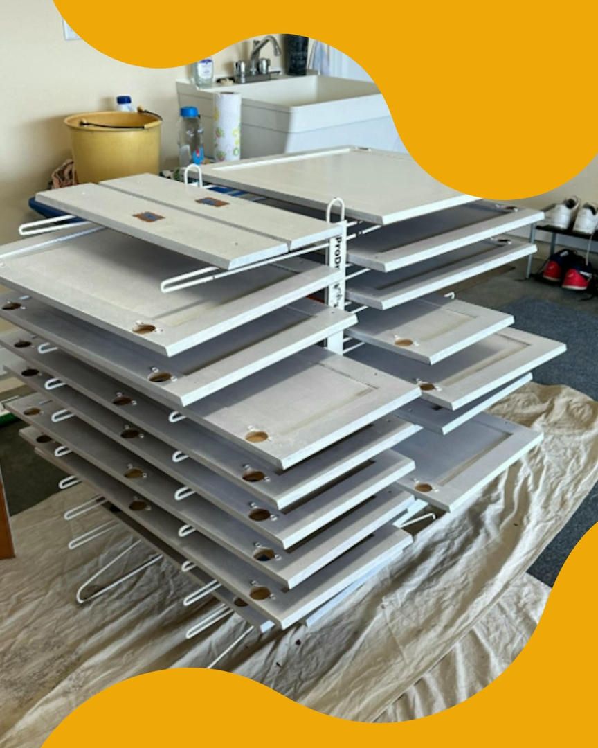 Painted cabinet doors stacked on drying racks in a workshop.