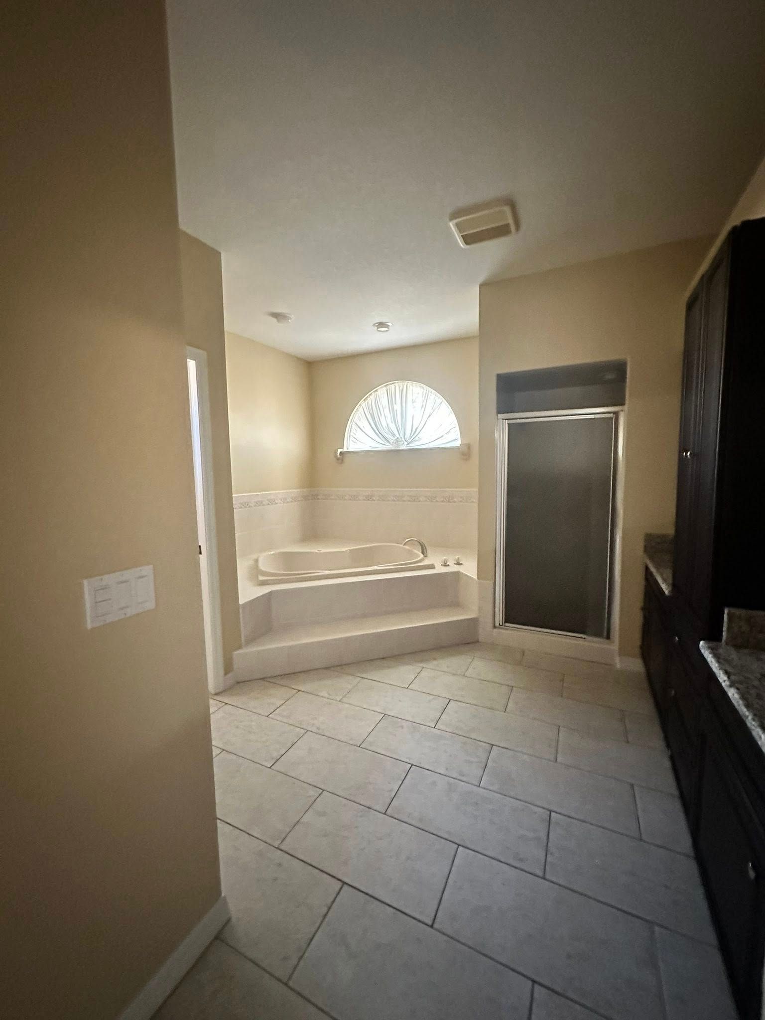 Bathroom interior with tiled floor, built-in tub, and dark cabinets.