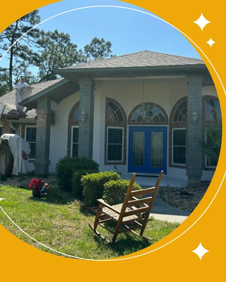 A house with blue double doors, arched windows, and a rocking chair on the lawn.