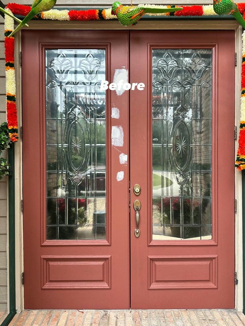 Red double doors with glass panels and a colorful garland, 