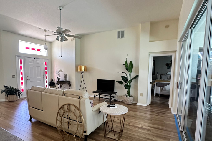 Modern kitchen with wooden island, stools, and gray cabinets. Pendant lights hang above.