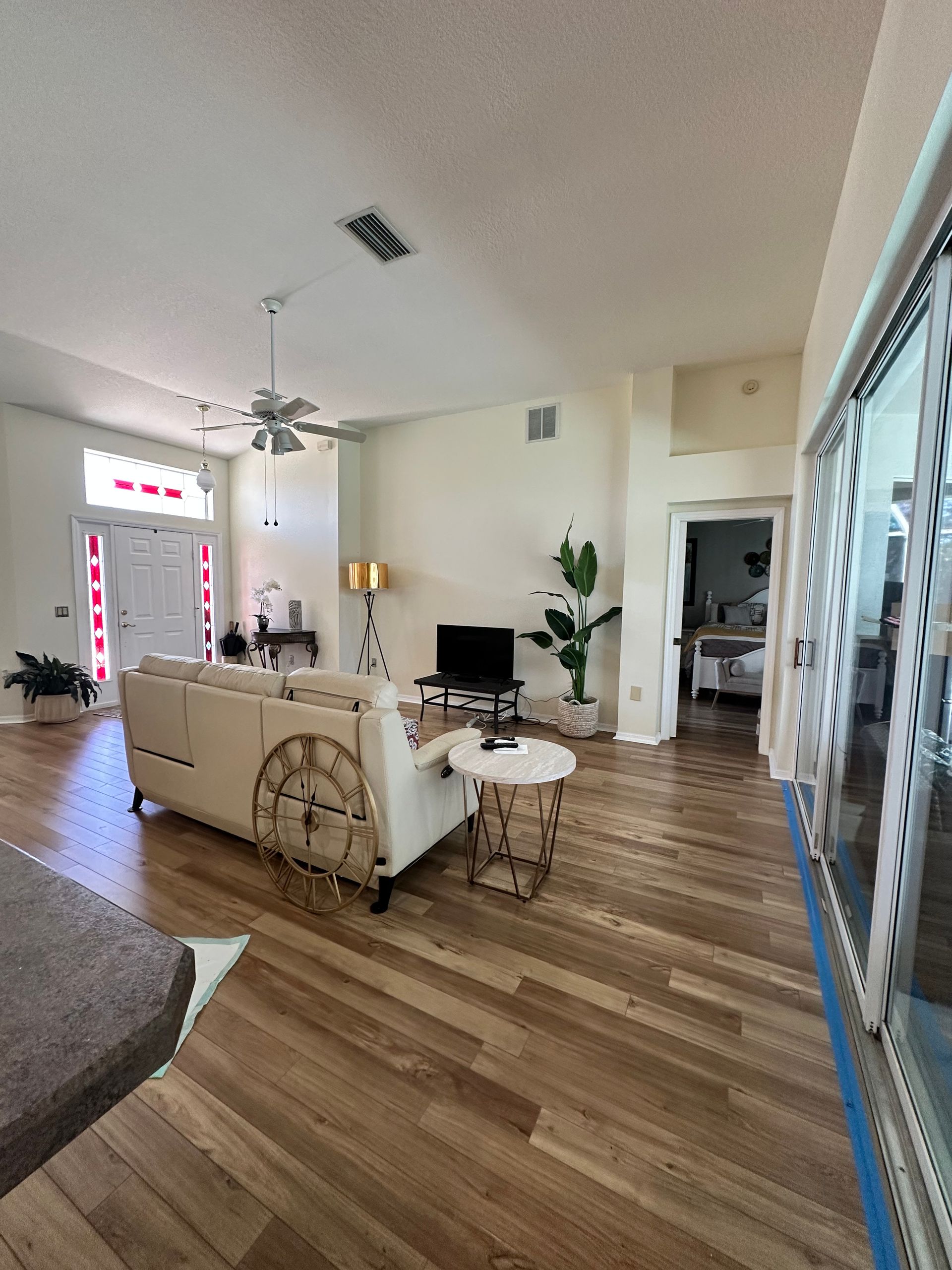 Living room with hardwood floors, sofa, TV, and sliding glass doors.