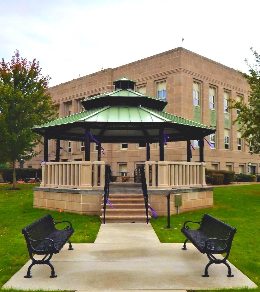 a wooden walkway leading to a gazebo overlooking a body of water at sunset .