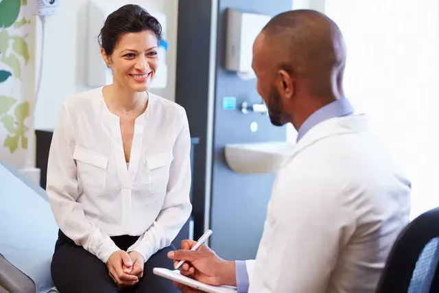 A woman is sitting in a hospital bed talking to a doctor.