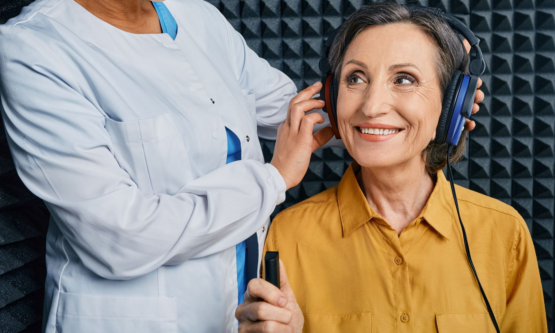 An elderly woman is getting her hearing tested by a doctor.