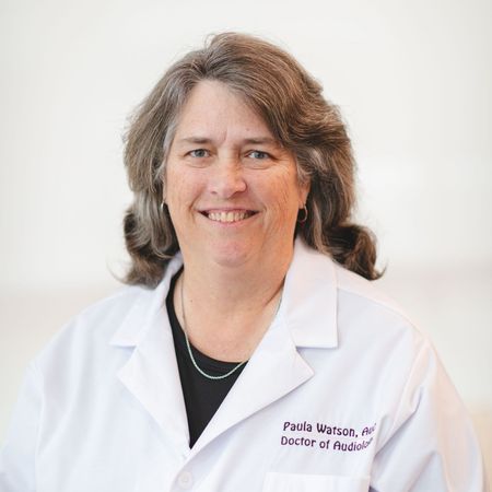 A woman in a white lab coat is smiling for the camera