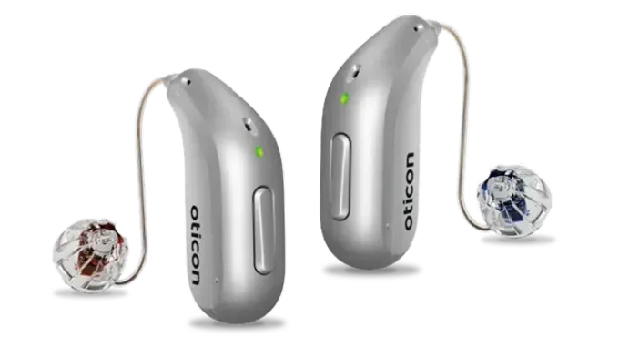 A pair of silver hearing aids made by oticon