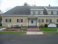 A large yellow house with a black roof and a white porch.