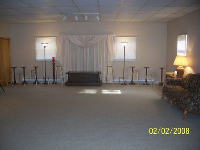 A room with a couch , chairs , lamps and a coffin in it.