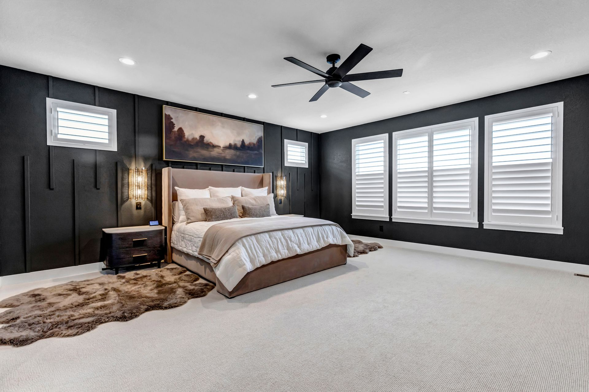 Modern bedroom with dark accent wall, king bed, rug, and white shutters.