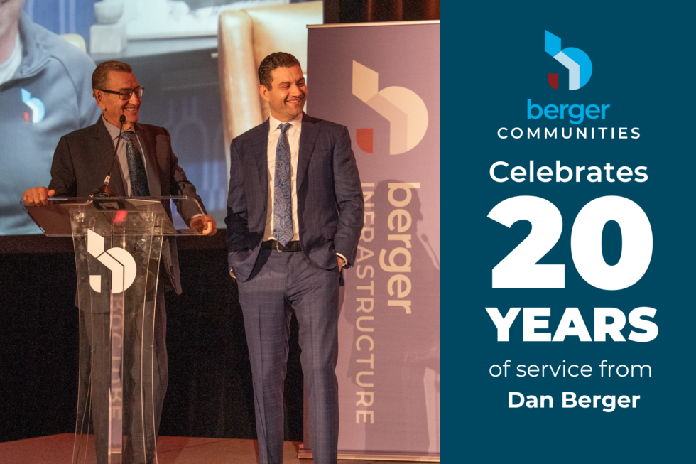 Two men in suits standing at a podium for a Berger Communities 20-year service celebration for Dan Berger.