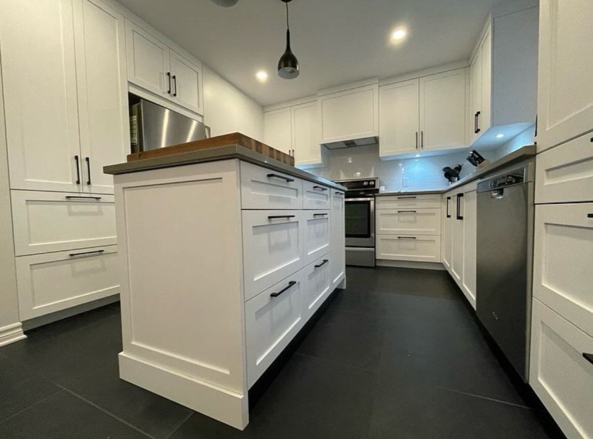 Une cuisine avec des armoires blanches et un grand îlot au milieu.