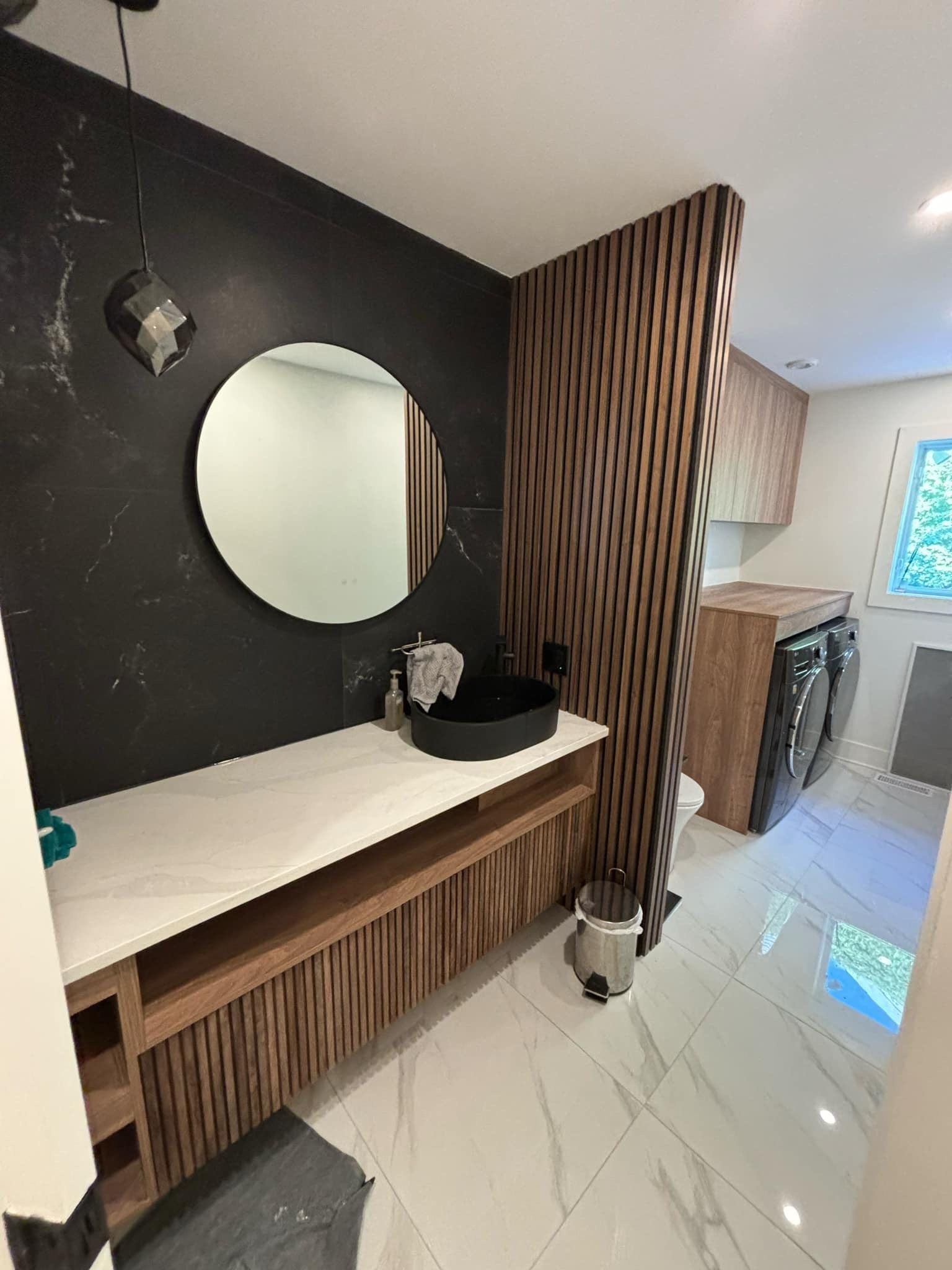 Une salle de bain avec lavabo, miroir et machine à laver.