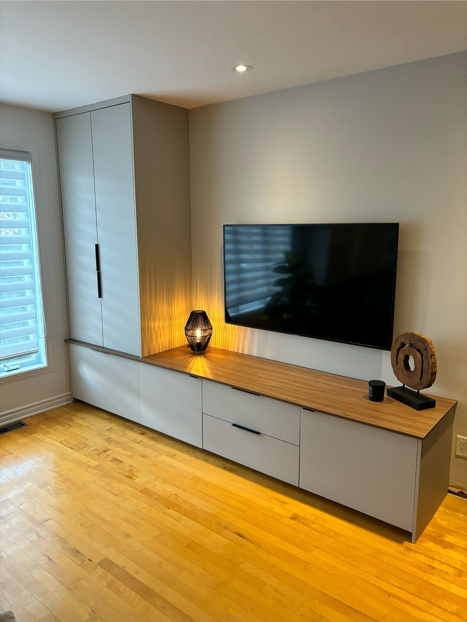 Un salon avec parquet et une télévision écran plat au mur.