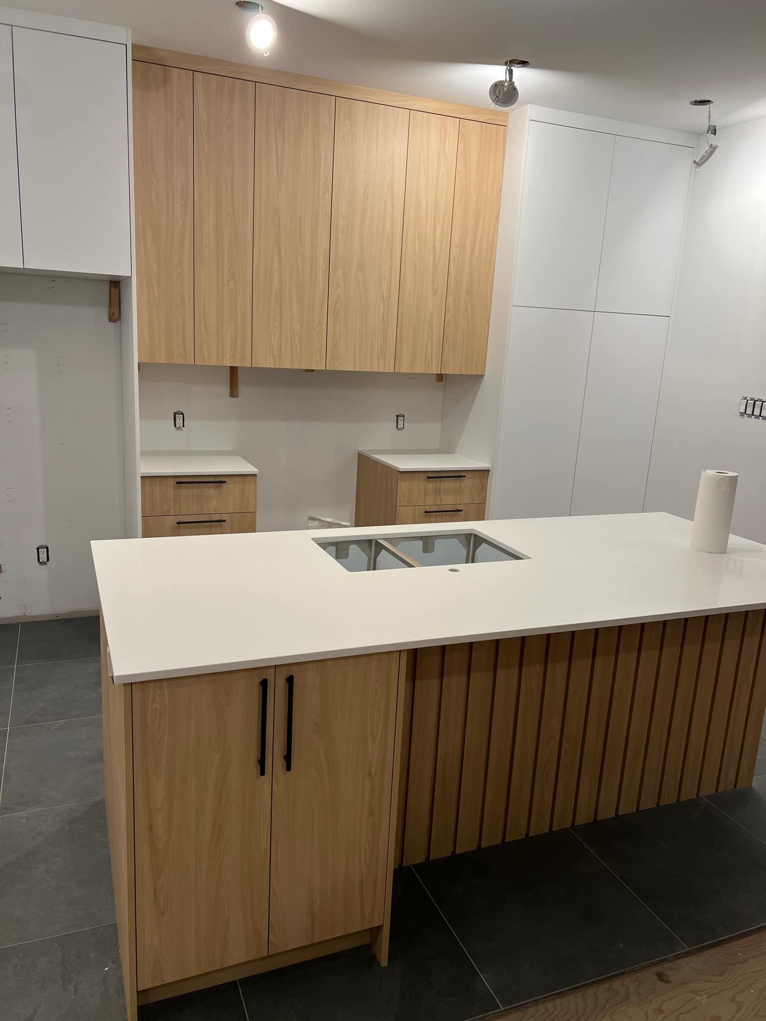 Une cuisine avec des armoires en bois et un comptoir blanc