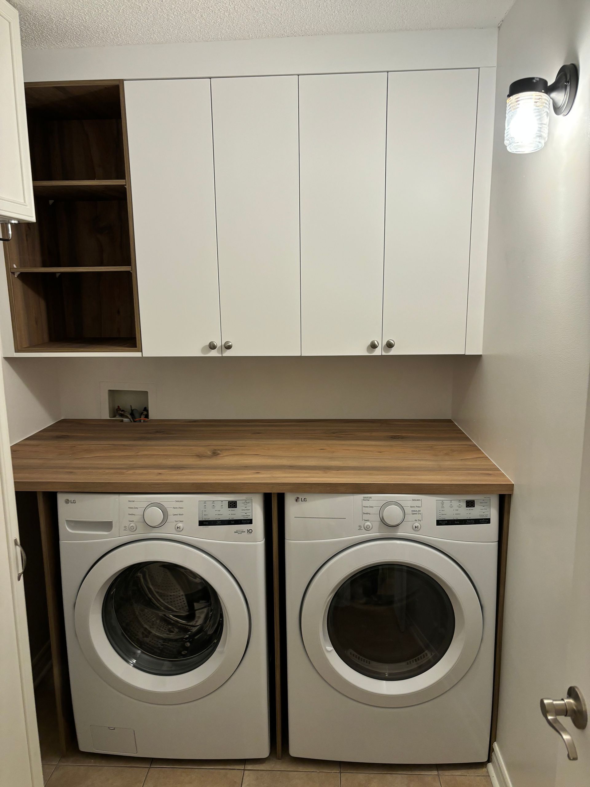 Une buanderie avec deux machines à laver et un plan de travail en bois.