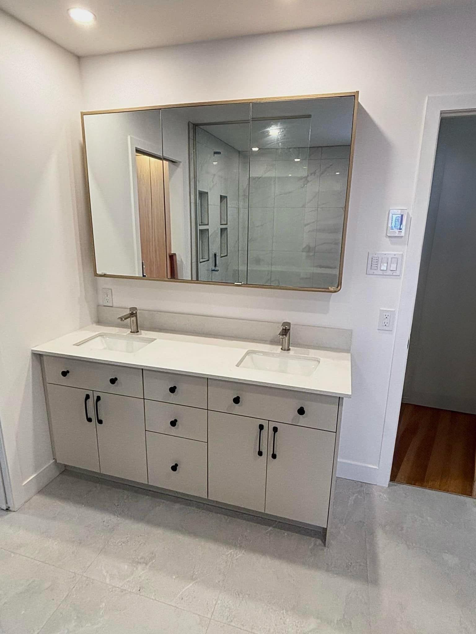 Une salle de bain avec deux lavabos et un grand miroir.