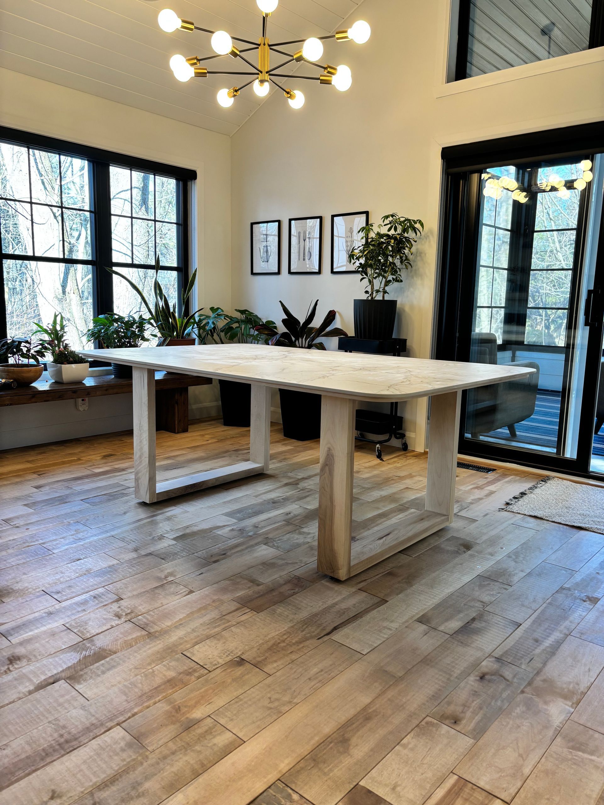 Une grande table en bois est posée dans un salon à côté d'une porte coulissante en verre.
