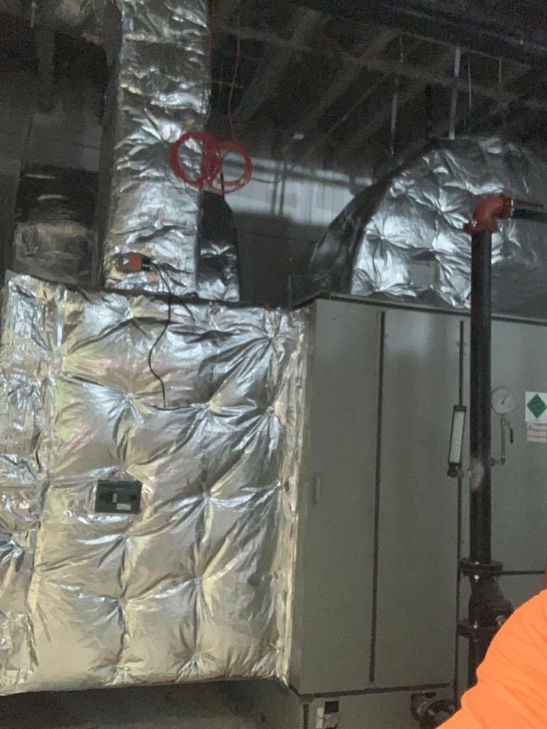 Insulated HVAC equipment with a red valve. Metallic silver insulation covers the machinery.