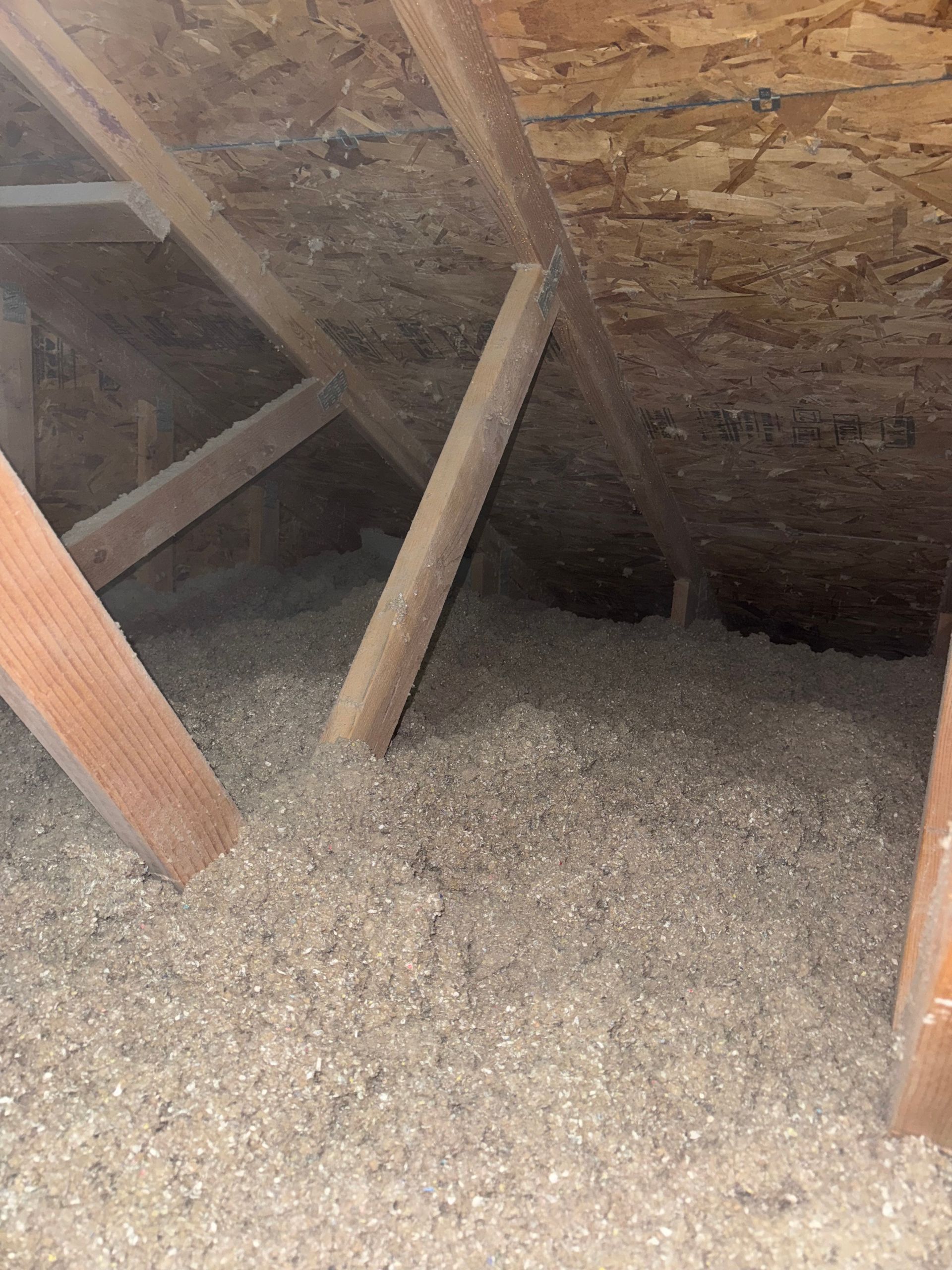 Attic with wood framing, insulation, and beams.