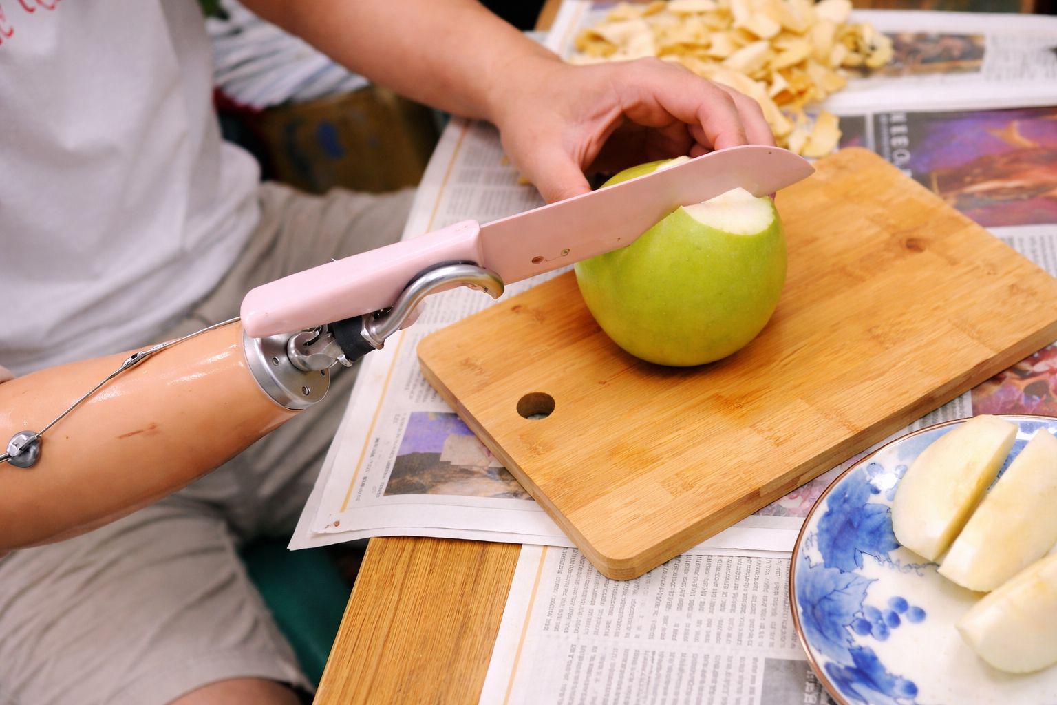 永純功能手 Body-Powered Prosthetics：實用情境展示，利用功能手義肢，穩固地在砧板上切削蘋果。