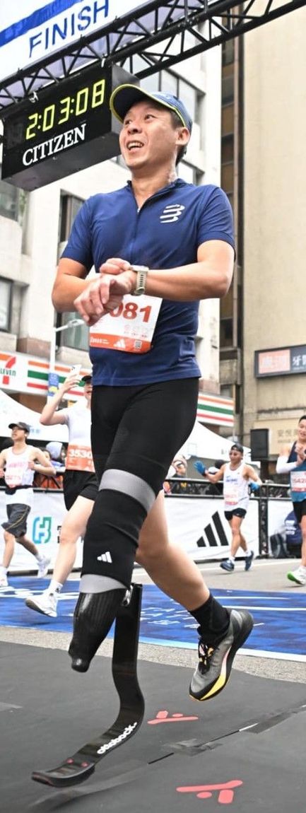 永純之友周柏宏：馬拉松衝線瞬間的動態特寫，穿戴 Ottobock 專業碳纖維儲能跑步腳掌（刀鋒腳），膝蓋處配有黑色加壓護套，呈現極具力量感的跑步步態。