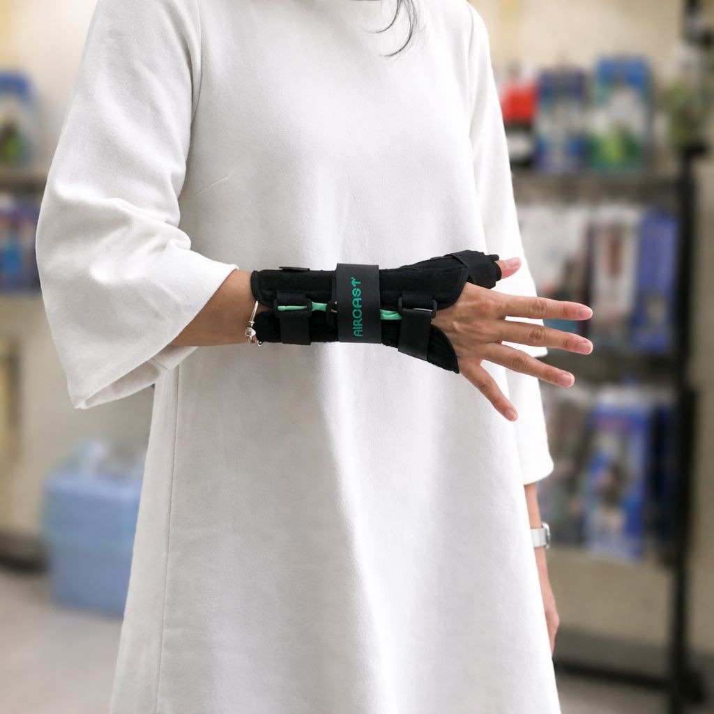 永純手托板 Wrist Brace：黑色布面結合綠色 AirCast 標誌中帶，呈現符合人體工學的掌托弧度與快拆式固定扣。