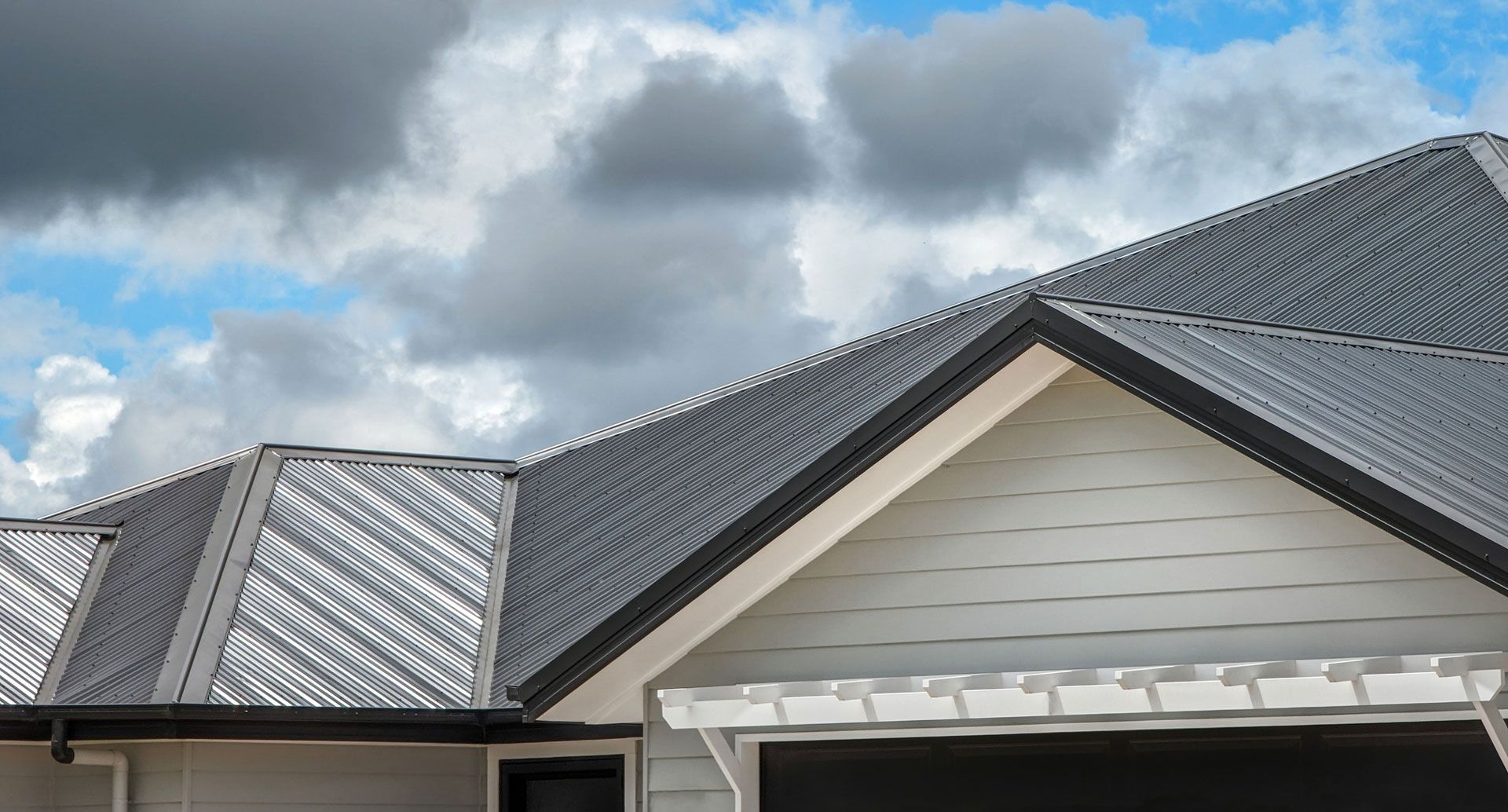 A white house with a gray roof and a cloudy sky in the background.