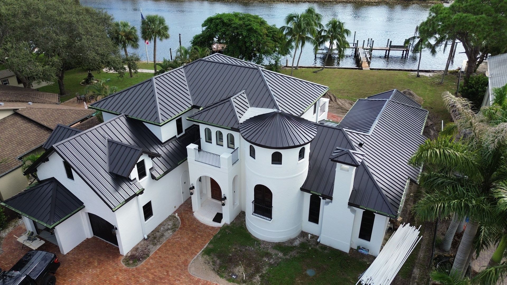 White house with black roof, featuring turrets, overlooking a body of water and docks.