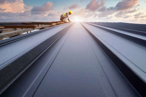 Commercial roofer fitting metal roof panels with drills—expert craftsmanship in action.